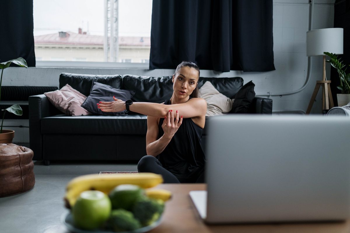 A coach relaxing at home with a laptop closed beside her